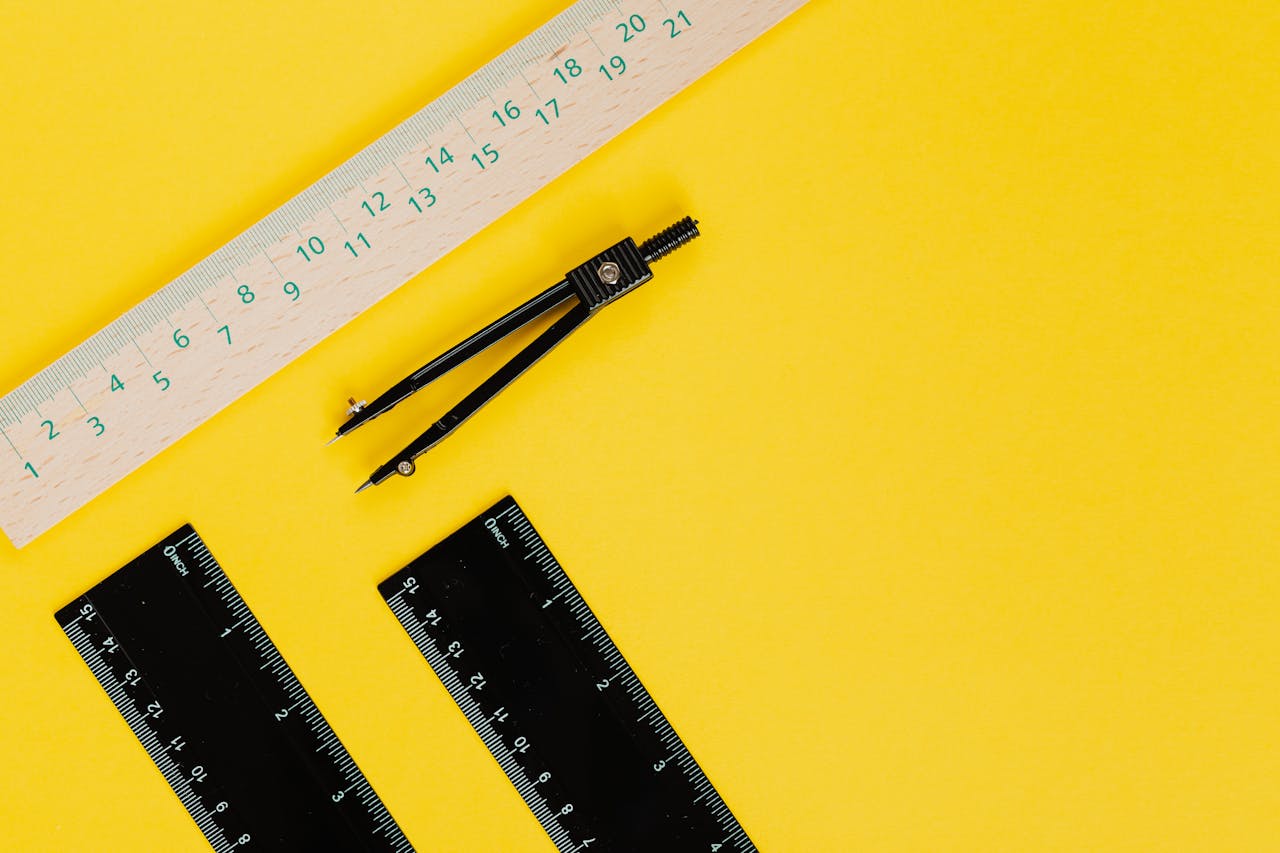 Vibrant still life of compass and rulers on a yellow background.
